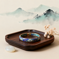 Handmade cloisonne enamel bracelet on dark wood tray with jade and dried flowers