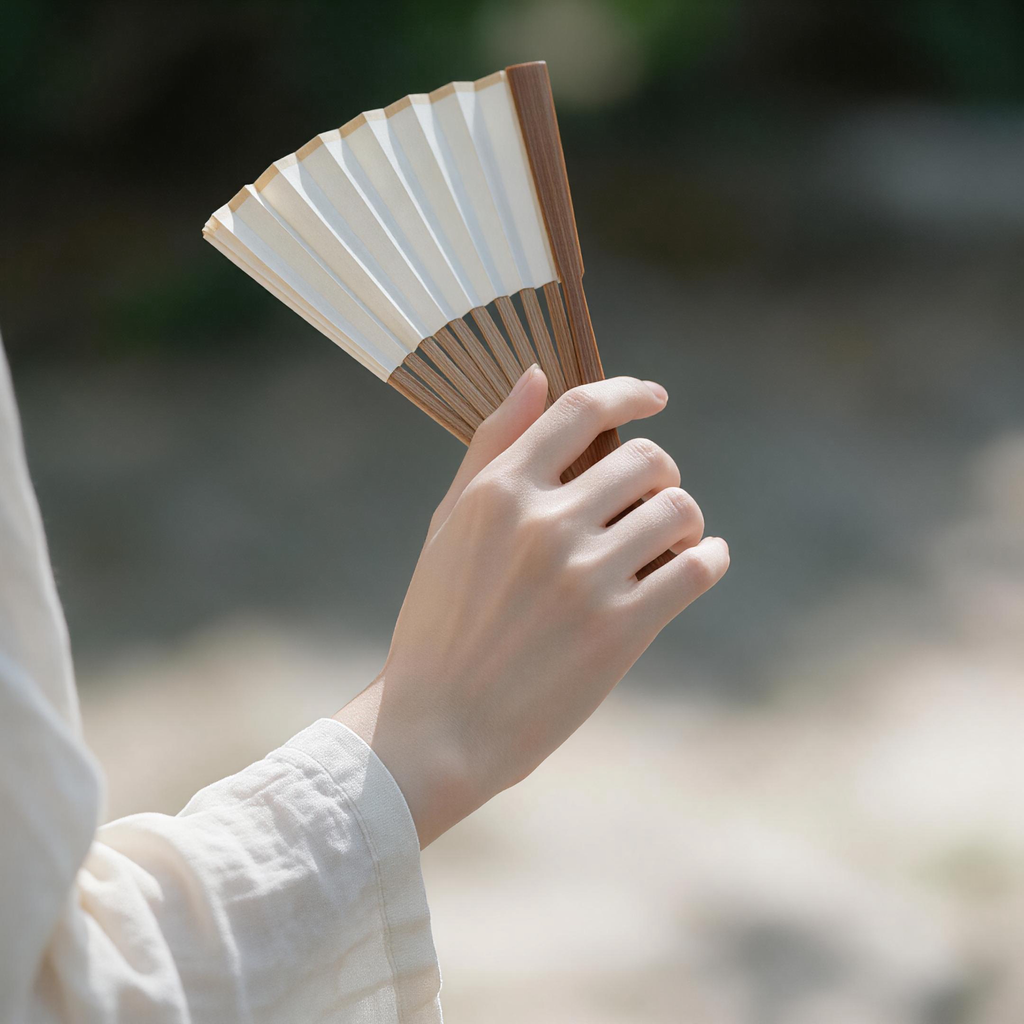 Hand holding Chinese folding fan, wrist and fan close-up